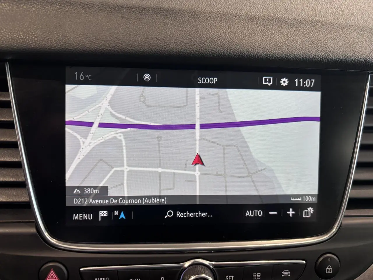 Écran tactile du système de navigation intégré dans le tableau de bord de l'Opel Grandland rouge foncé.