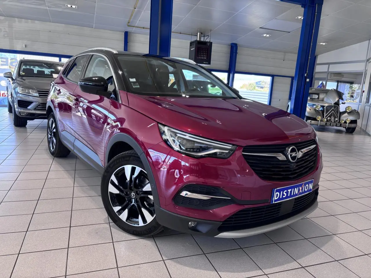 Opel Grandland rouge foncé en 3/4 avant droit, avec jantes alliage noires et toit noir en showroom.