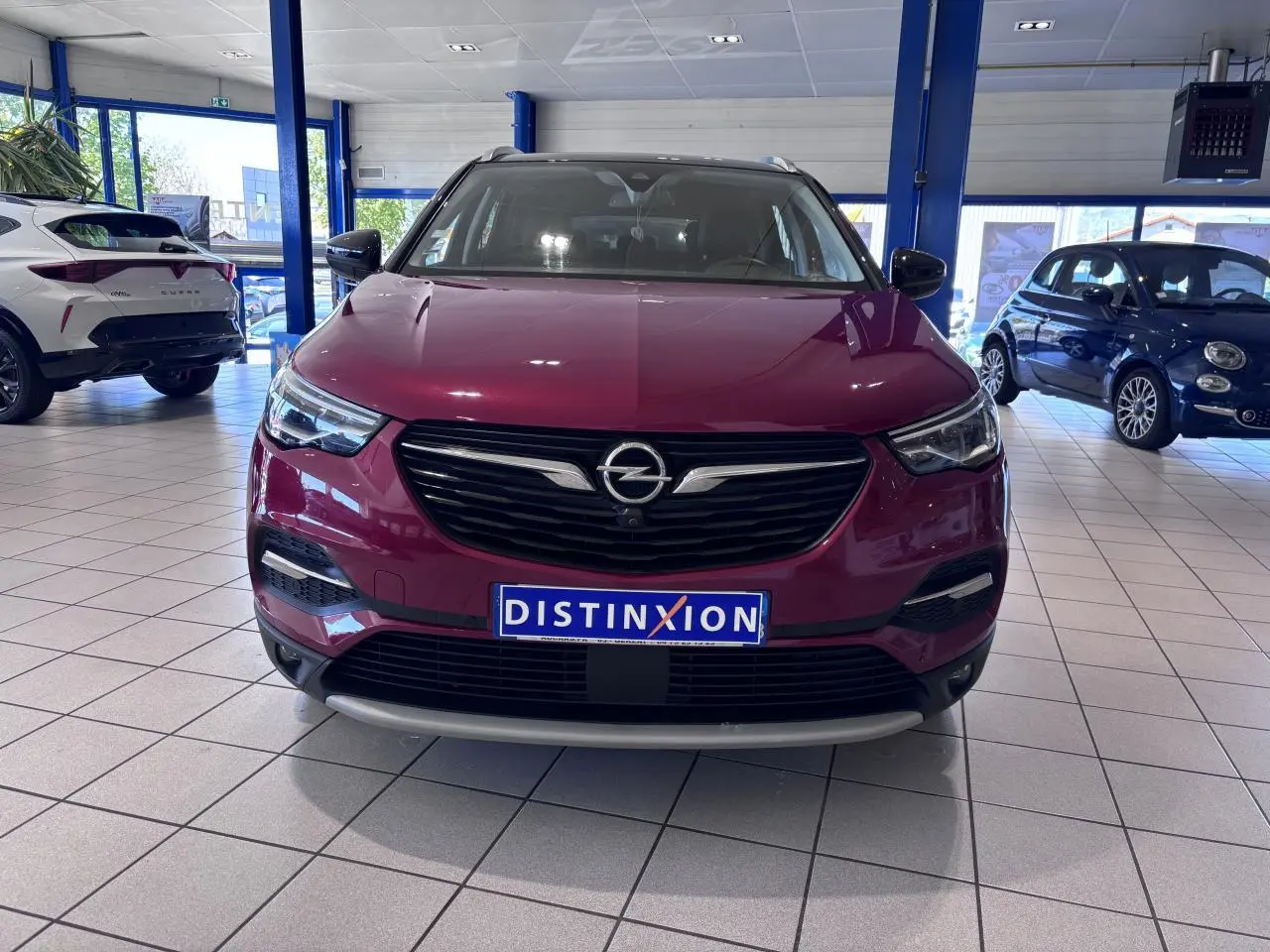 Vue de face d'un Opel Grandland rouge foncé avec calandre noire et détails chromés, en showroom lumineux.