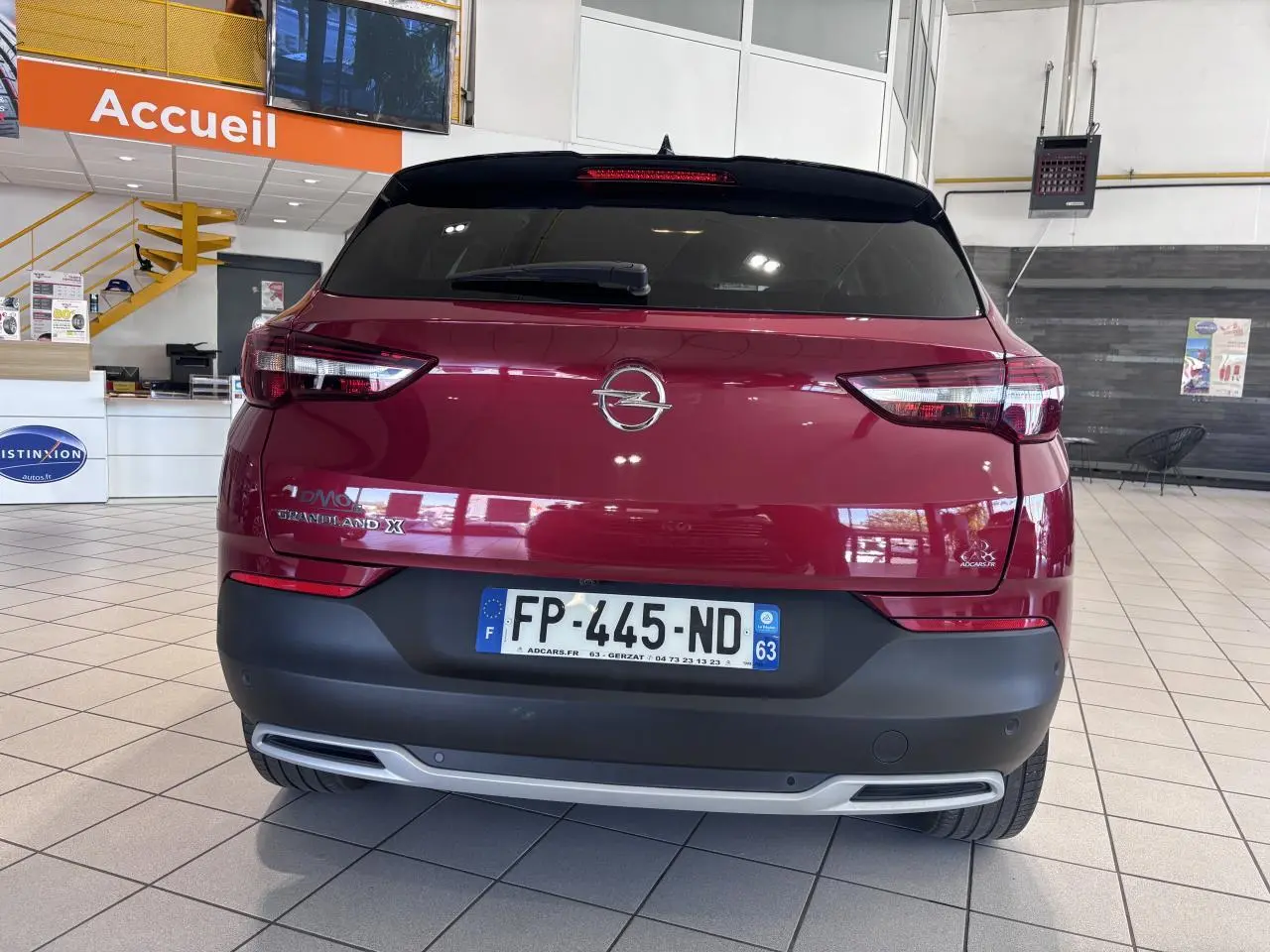 Vue arrière d'un Opel Grandland X rouge foncé avec hayon motorisé et feux arrière LED dans un showroom.