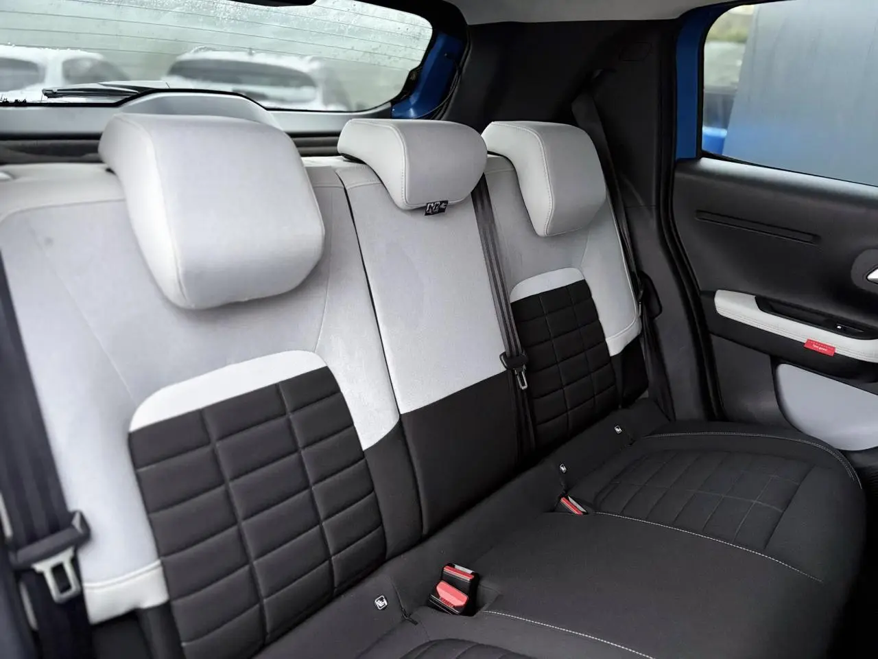 Vue intérieure du siège arrière bicolore noir et gris de la Citroën C3 Turbo 100 Max, avec appuie-têtes et ceinture de sécurité.