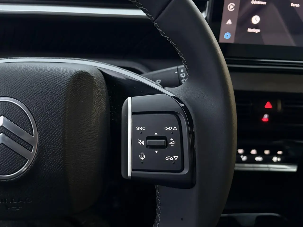 Gros plan sur le volant côté gauche de la Citroën C3 2025, avec commandes audio et micro intégrées, intérieur noir.