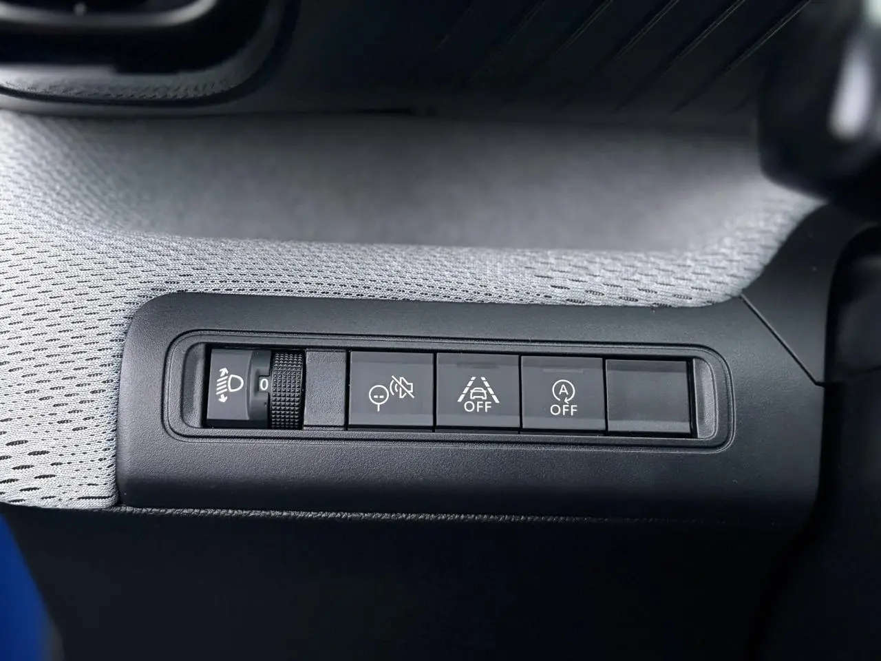 Gros plan sur les commandes de sécurité et d’éclairage côté gauche du tableau de bord de la Citroën C3 Bright Blue 2025.