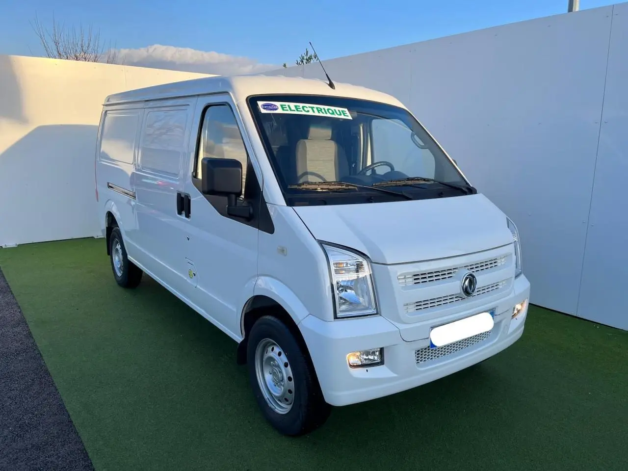 Fourgon blanc SERES DFSK EC35 électrique vu en 3/4 avant droit avec autocollant "ELECTRIQUE" sur pare-brise.