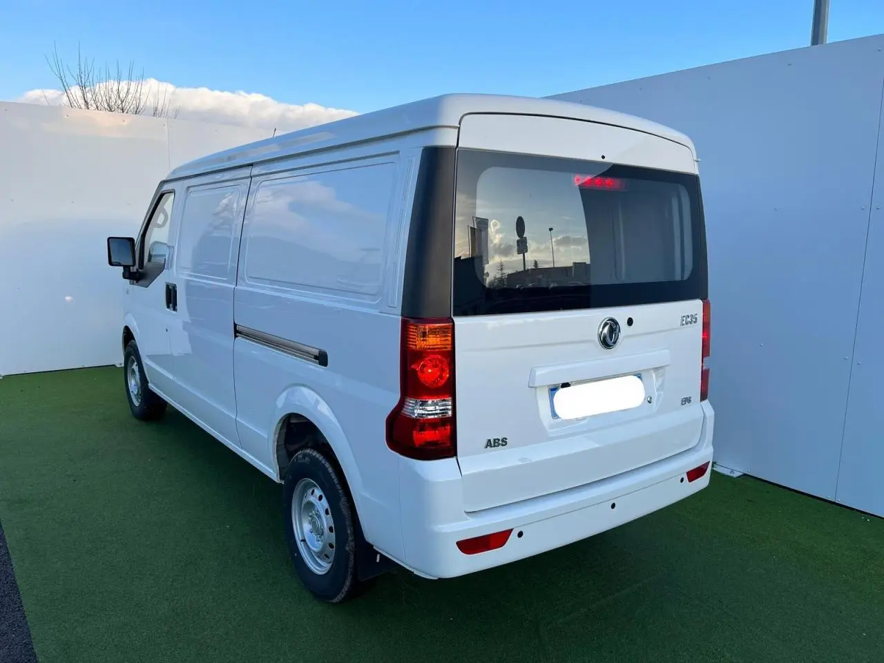 Vue 3/4 arrière droite d'un fourgon blanc SERES DFSK EC35 100% électrique avec porte latérale coulissante et feux arrière visibles.