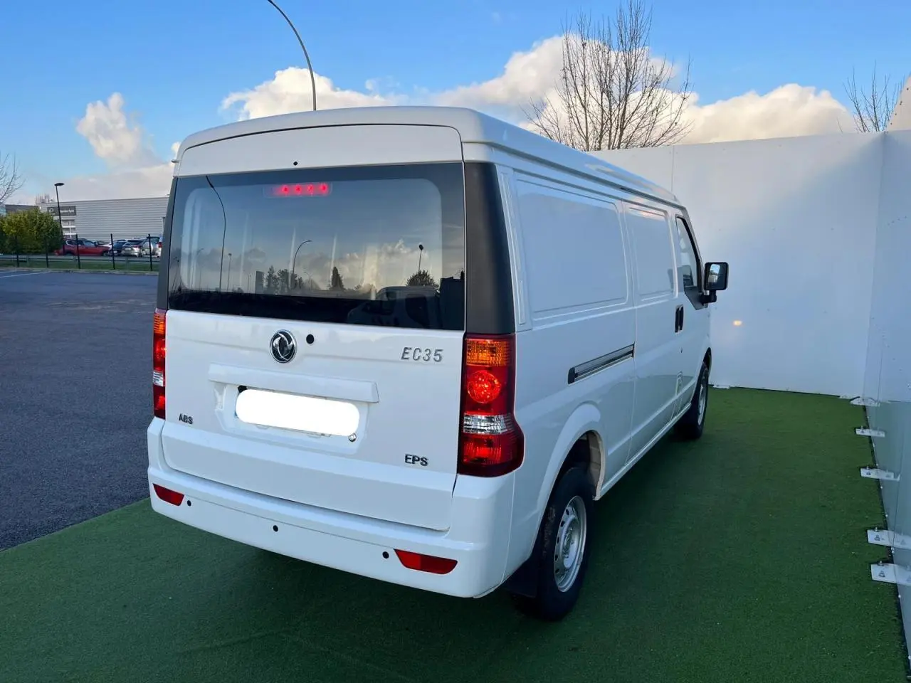 Vue arrière droite du fourgon blanc SERES DFSK EC35 électrique 2022 avec vitres teintées et feux arrière allumés.