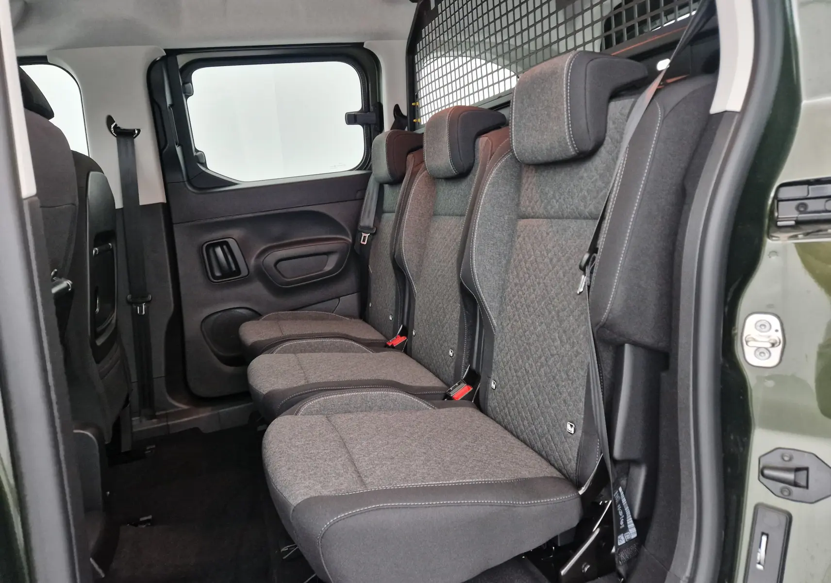 Vue latérale intérieure du combo life vert sirkka montrant les trois sièges individuels arrière et la grille de séparation.