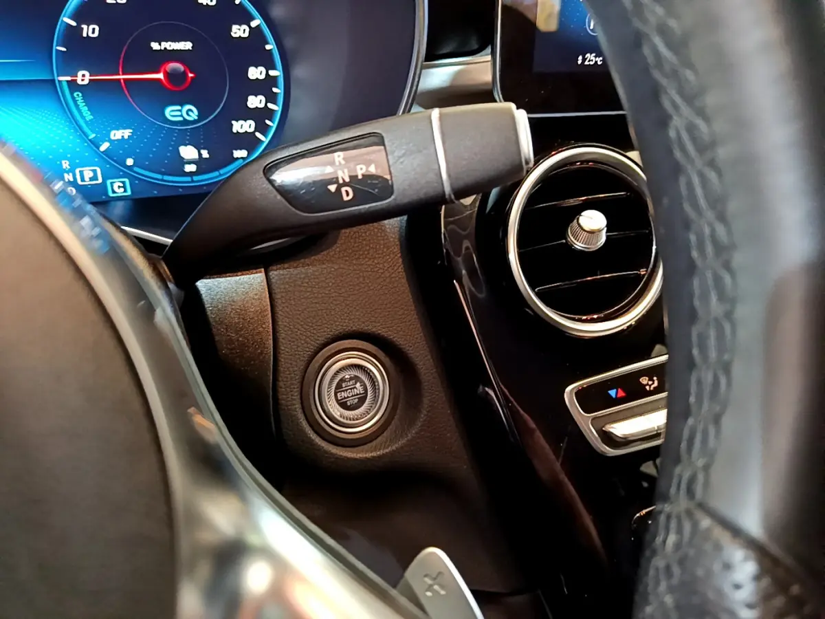 Détail intérieur côté gauche du tableau de bord du Mercedes GLC 300 E AMG Line avec bouton démarrage et levier de vitesses.