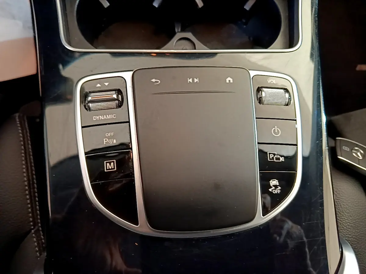 Gros plan sur la console centrale noire brillante du Mercedes GLC 300 E AMG Line 2021 avec commandes tactiles et molette volume.