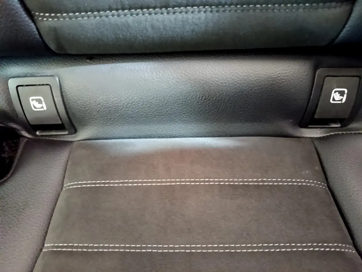 Gros plan sur la commande de rabattement des sièges arrière en cuir noir avec surpiqûres blanches dans un Mercedes GLC 300 E AMG Line.