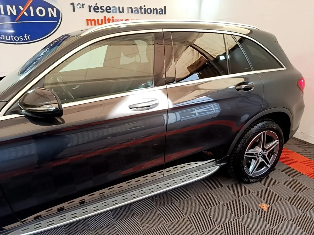 Vue latérale droite d'un Mercedes GLC 300 E AMG Line gris foncé avec jantes étoile et marchepied aluminium.