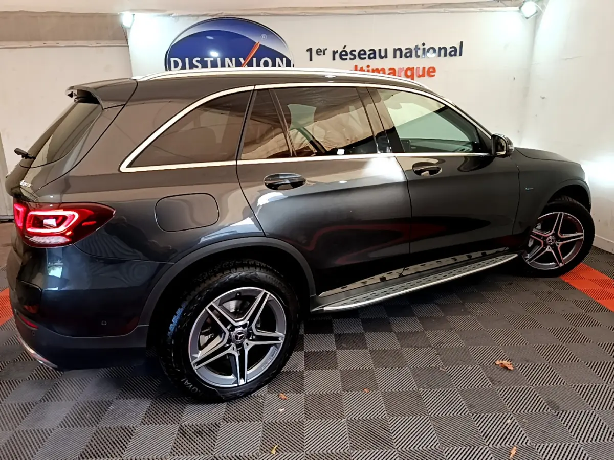 Vue côté gauche arrière d'un Mercedes GLC 300 E AMG Line gris foncé avec jantes alliage et rails de toit chromés.