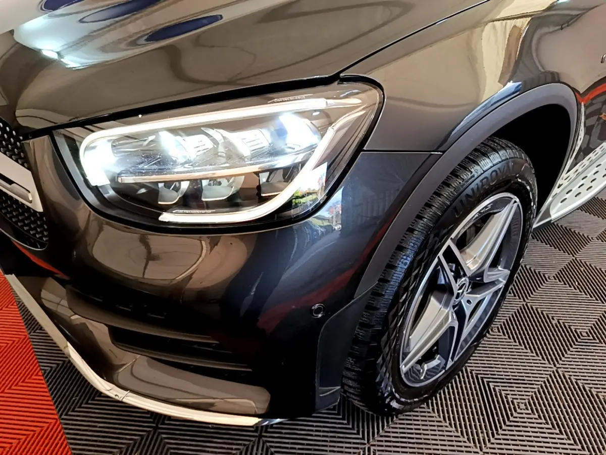 Gros plan sur l'avant droit gris foncé du Mercedes GLC 300 E AMG Line avec phare LED et jante étoile AMG.