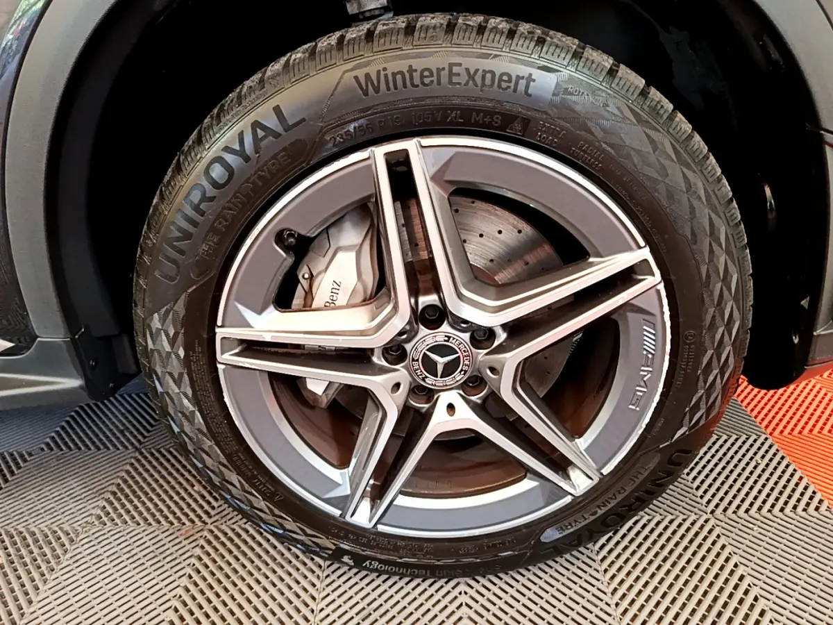 Gros plan sur la roue avant droite du Mercedes GLC 300 E AMG Line gris foncé avec jante AMG et pneu hiver Uniroyal.