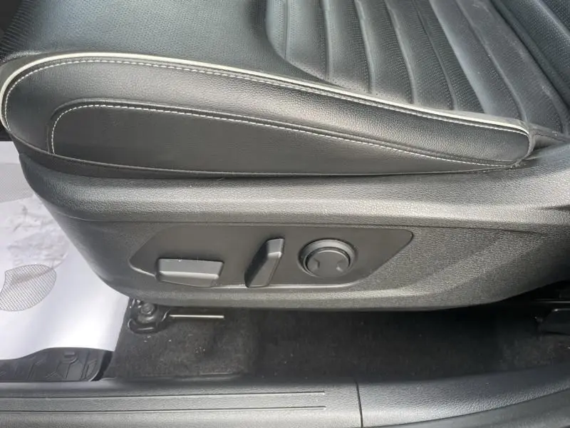 Gros plan sur les commandes de réglage électrique du siège conducteur en cuir noir du Kia Sportage vert métal 2022.