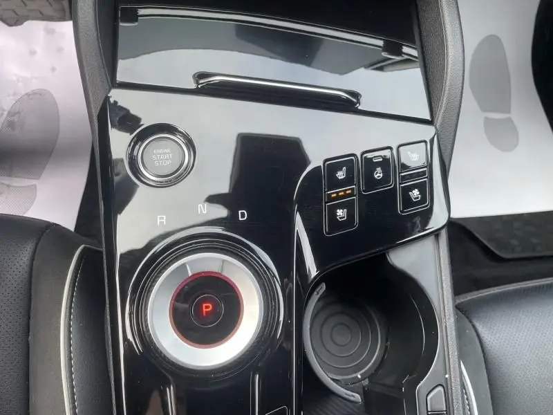 Gros plan sur la console centrale noire brillante du Kia Sportage 2022, avec molette de boîte auto et boutons de sièges chauffants.