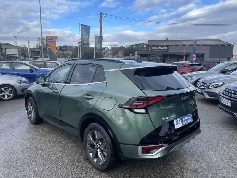 Vue 3/4 arrière droite d’un KIA Sportage 2022 vert métal avec toit noir et feux arrière LED distinctifs.