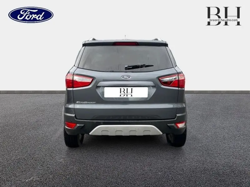 Vue arrière d'un Ford EcoSport 1.5 TDCi 95ch Titanium gris Smoke avec feux arrière LED et barres de toit visibles.