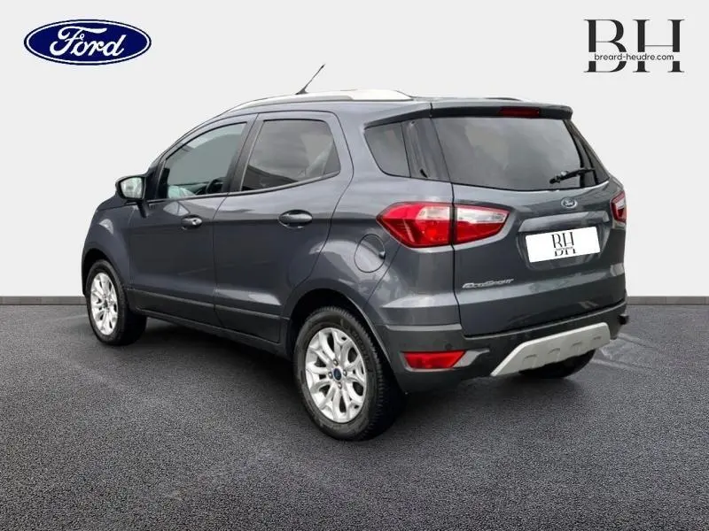 Vue 3/4 arrière droite d'un Ford EcoSport 2017 gris Smoke avec jantes alu et barres de toit visibles.