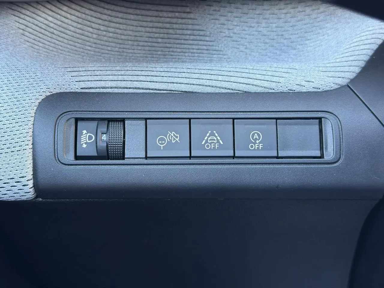 Gros plan sur les commandes de réglage des phares et d'assistance à la conduite dans une Citroën C3 Rouge Elixir.