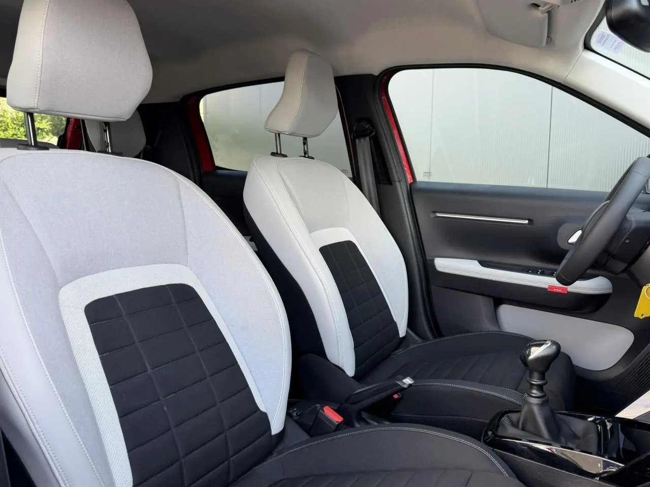 Vue intérieure côté droit des sièges avant gris clair et noir d'une Citroën C3 Rouge Elixir avec boîte manuelle.