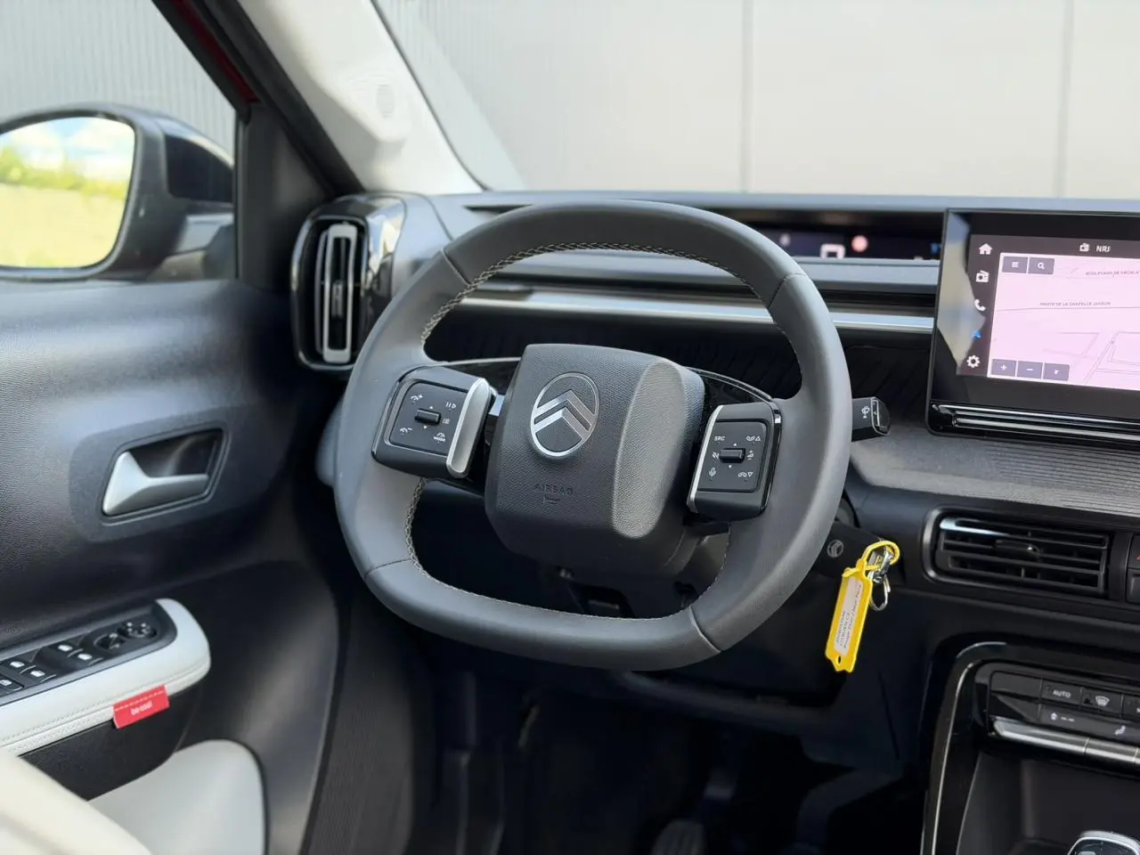 Vue intérieure centrée sur le volant multifonction noir de la Citroën C3 2025 avec écran tactile GPS à droite.