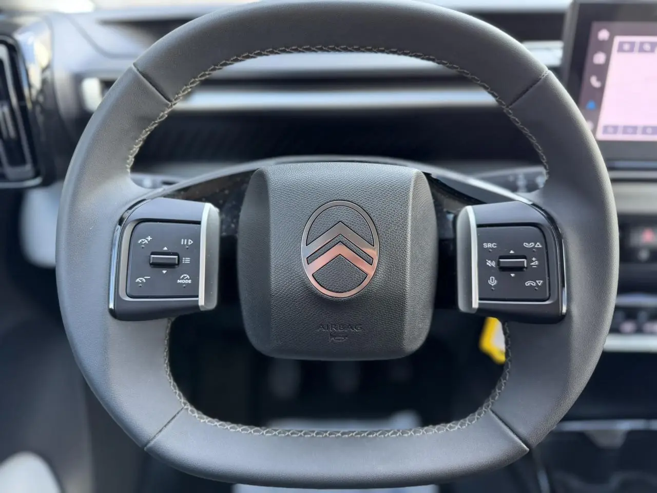 Gros plan sur le volant noir de la Citroën C3 Turbo 100 Max avec commandes intégrées et logo chromé central.