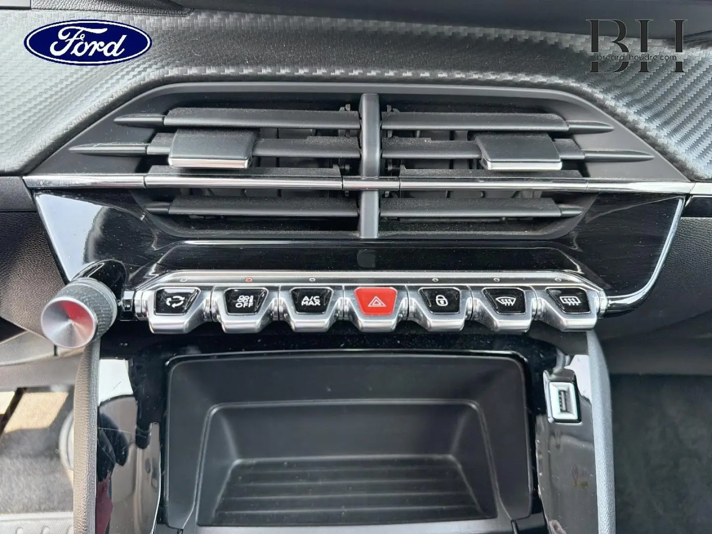 Tableau de bord avec commandes en rangée et aérateurs, intérieur noir brillant d'une Peugeot 208 gris Platinium.