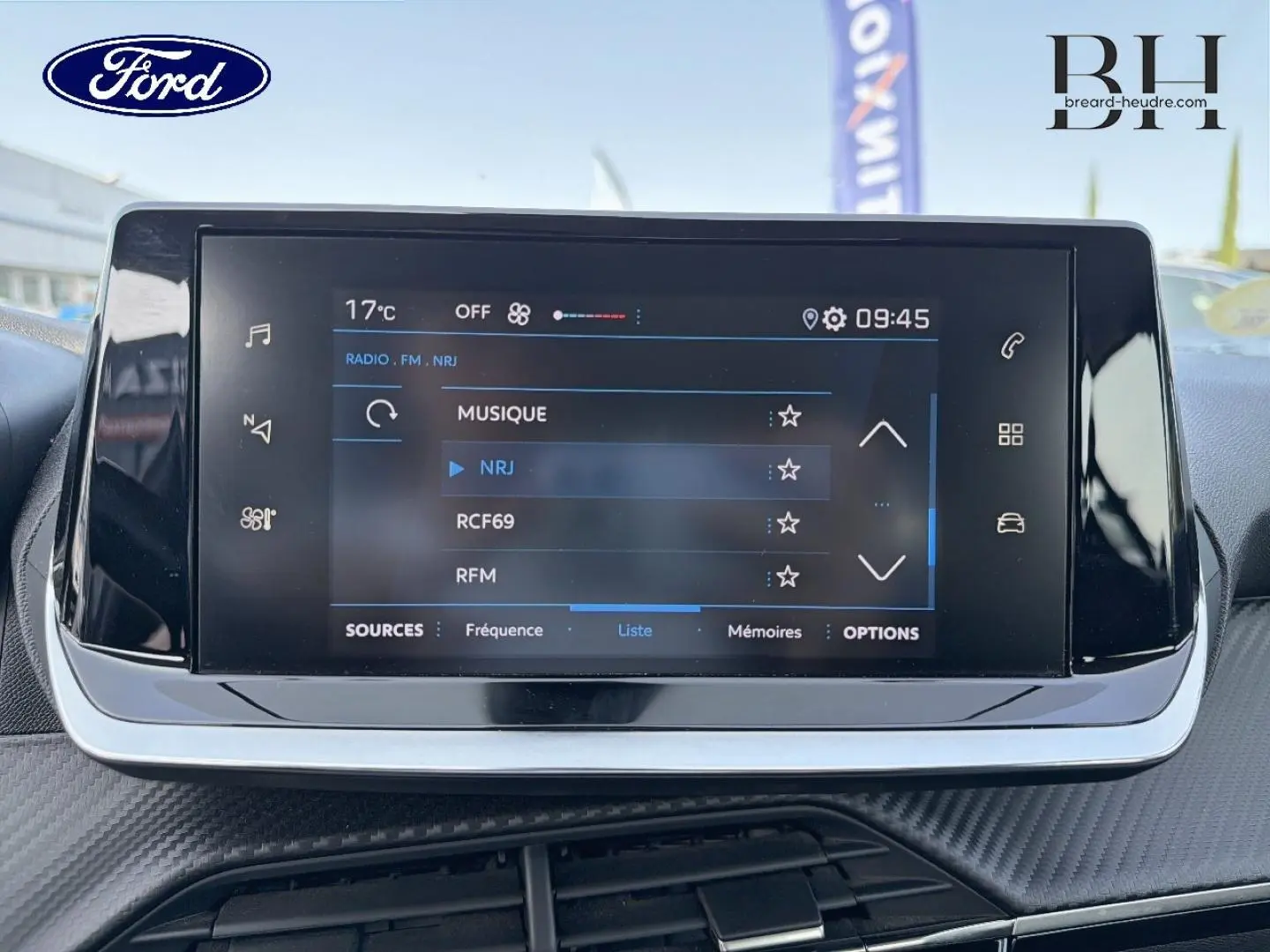 Écran tactile central du tableau de bord d'une Peugeot 208 1.5 BlueHDi, affichant les options radio FM.