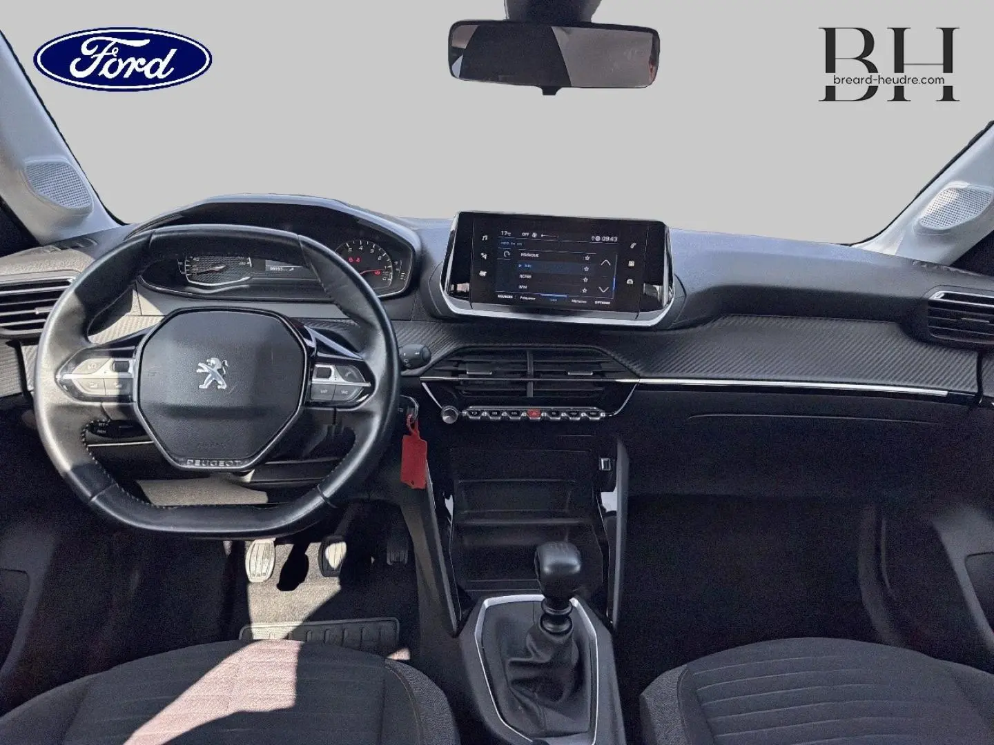 Vue intérieure avant du tableau de bord et volant noir d'une Peugeot 208 1.5 BlueHDi 2020 avec boîte manuelle.