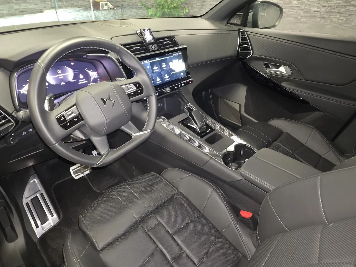 Intérieur noir cuir du DS7 Crossback 2025 vu côté conducteur, avec tableau de bord numérique et écran tactile central.