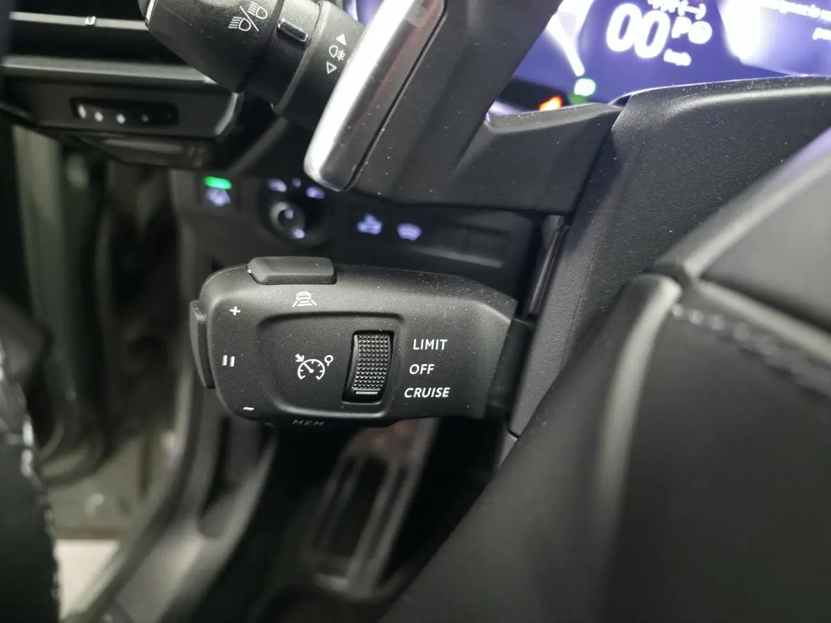 Gros plan sur la commande de régulateur de vitesse à gauche du volant du DS7 Crossback gris 2025, intérieur noir.