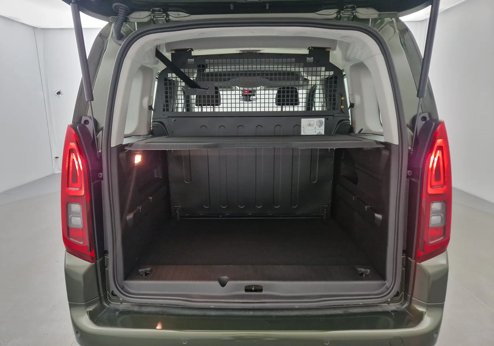 Vue arrière de l'Opel Combo Life vert Sirkka avec coffre ouvert et grille de séparation visible derrière les sièges.