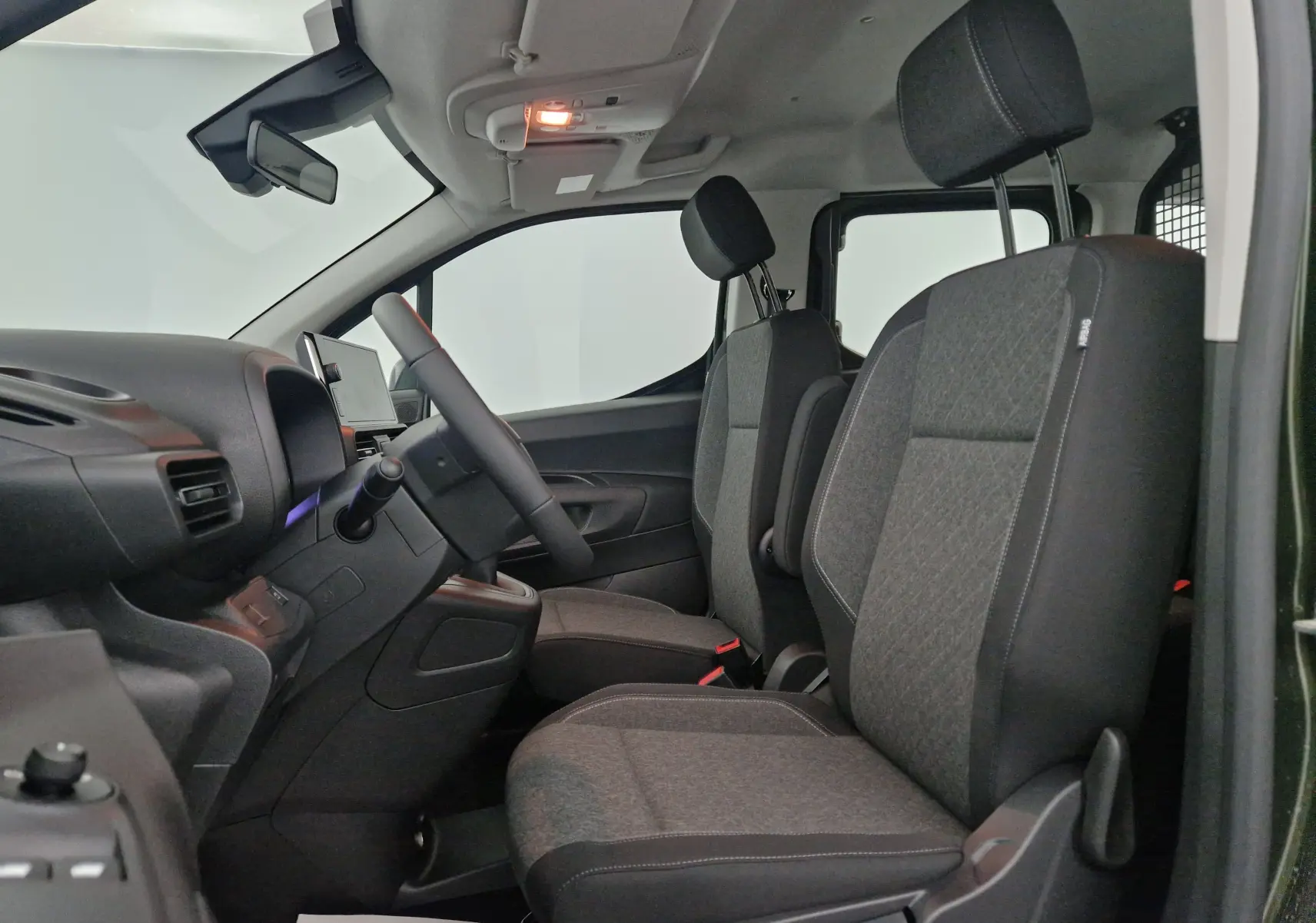 Vue intérieure côté gauche de l'Opel Combo Life vert Sirkka, montrant les sièges avant et la grille de séparation noire.