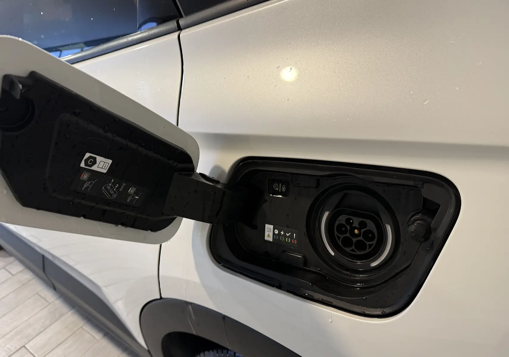 Prise de recharge ouverte côté gauche d’un Opel Grandland X blanc hybride rechargeable, vue rapprochée.
