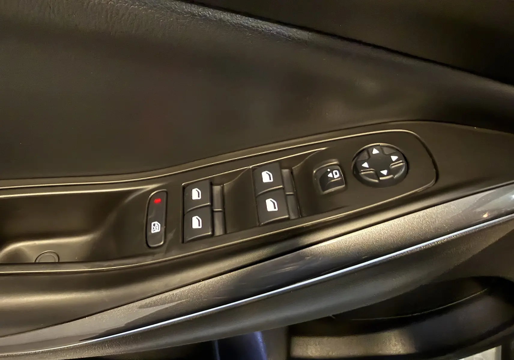 Gros plan sur les commandes de lève-vitres et réglage des rétroviseurs côté conducteur d’un Opel Grandland X hybride rechargeable.