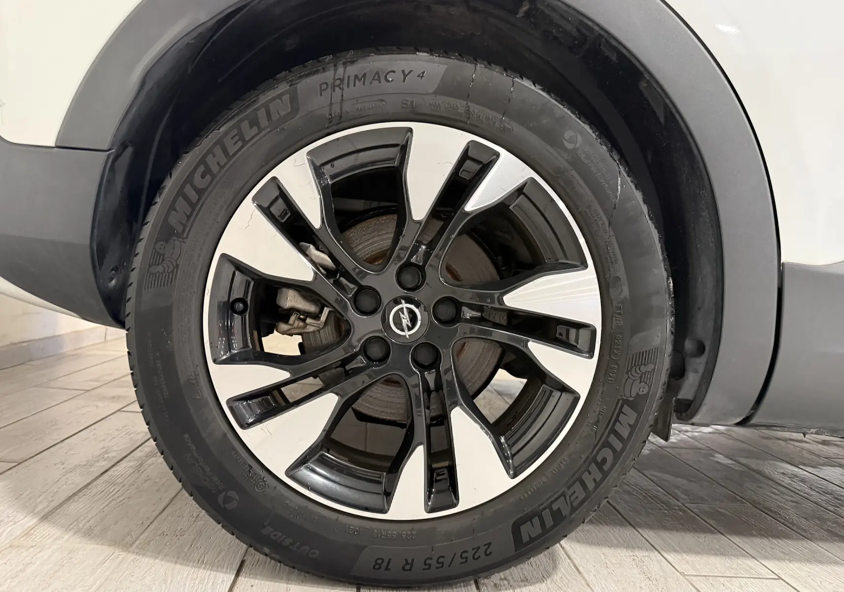 Gros plan sur la roue avant droite blanche et noire d’un Opel Grandland X hybride, pneu Michelin visible.