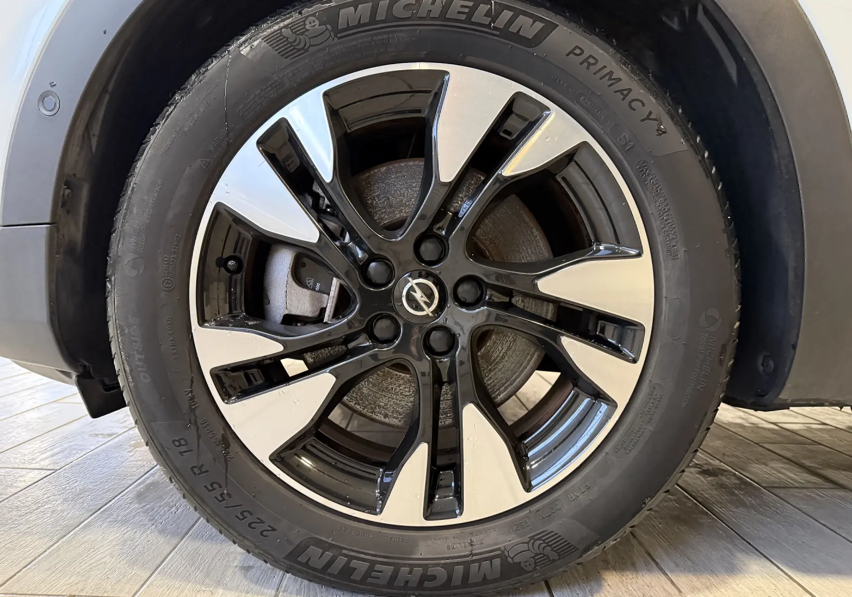 Gros plan sur la jante alliage bicolore noire et argentée d’un Opel Grandland X blanc, avec pneu Michelin visible.