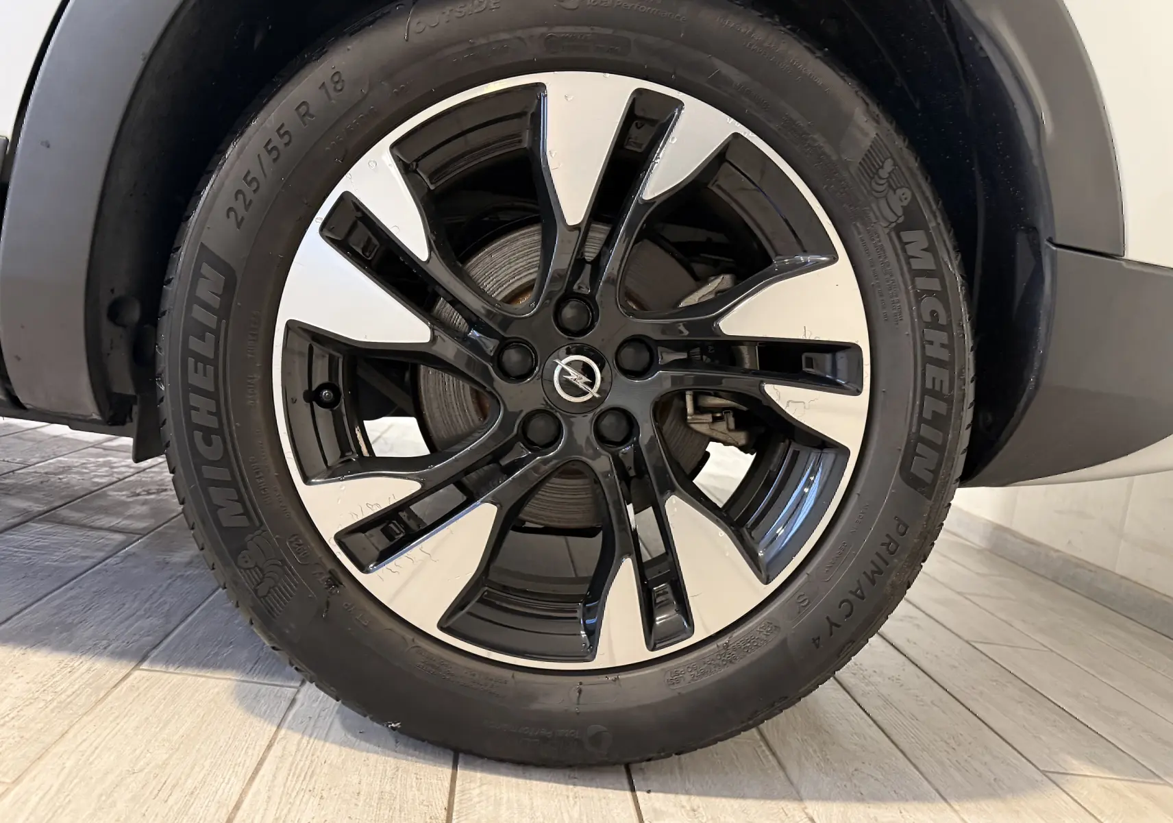 Gros plan sur la roue avant droite d’un Opel Grandland X blanc, jante alliage bicolore noire et argentée.