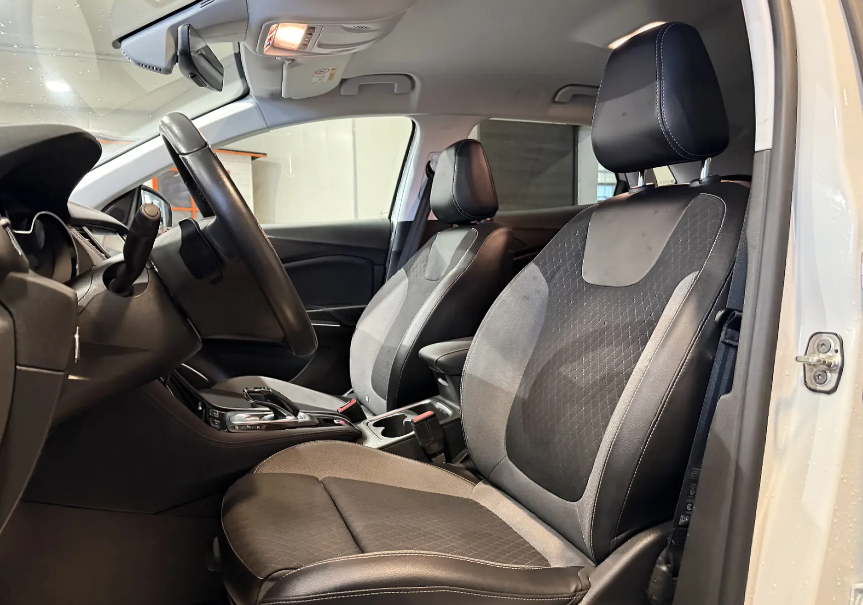 Vue intérieure côté conducteur de l’Opel Grandland X blanc, sièges mixtes cuir et tissu noir avec coutures blanches.