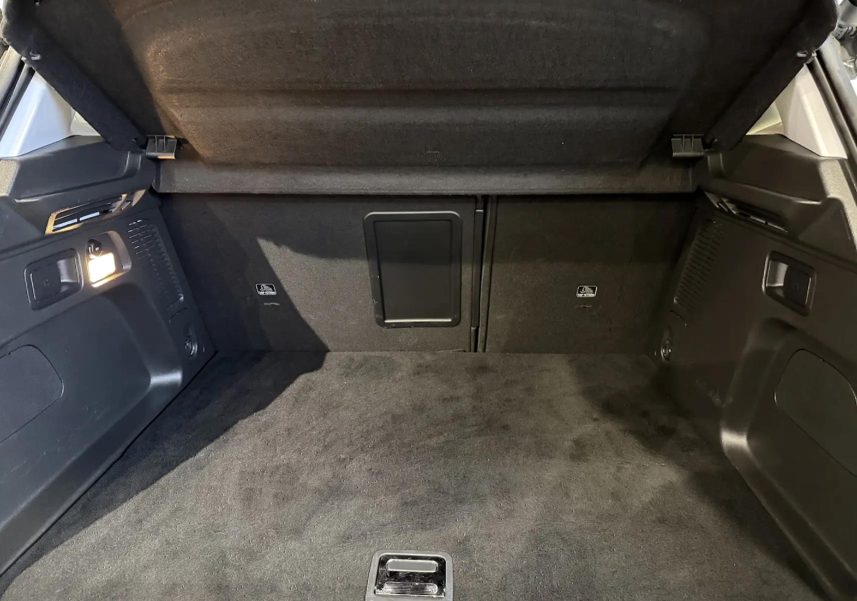 Vue intérieure du coffre noir d'un Opel Grandland X hybride rechargeable blanc, montrant l'espace et les finitions.