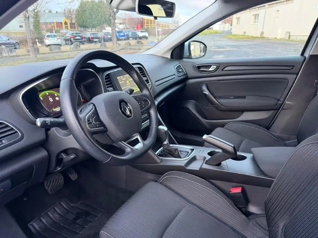 Vue intérieure côté conducteur de la Renault Mégane 2019, tableau de bord noir avec volant multifonction et écran central.
