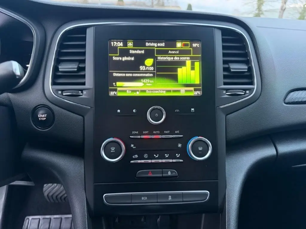 Vue rapprochée du tableau de bord de la Renault Mégane gris alu, avec écran tactile affichant l'eco-coaching et commandes climatisation.