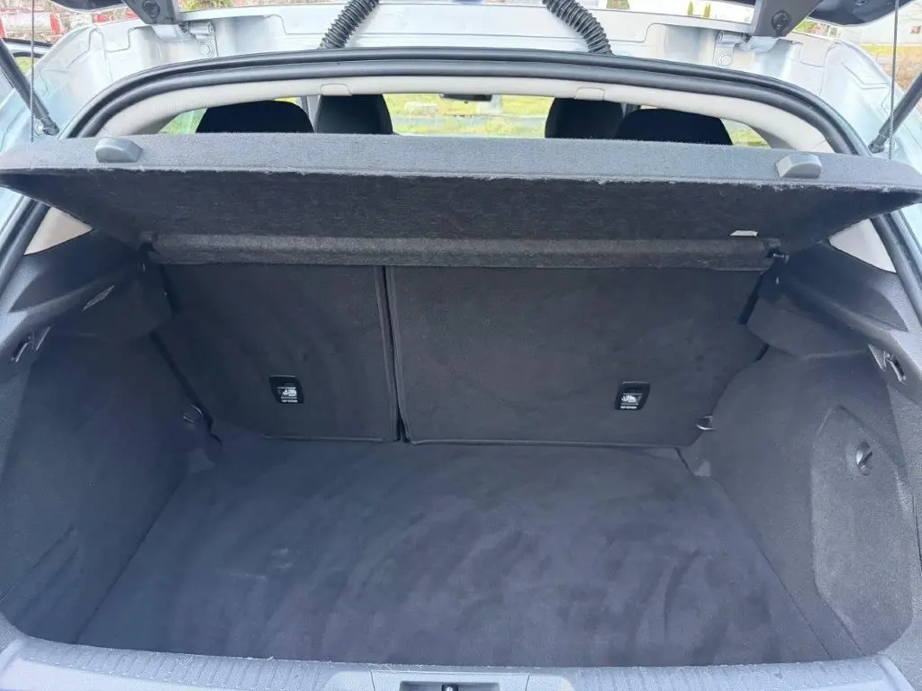 Coffre ouvert vu de l'arrière d'une Renault Mégane gris alu, montrant un espace de chargement propre et spacieux.