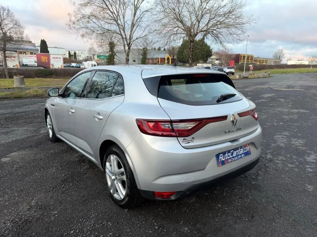 Renault Mégane gris alu vue 3/4 arrière droit sur parking, feux arrière LED et jantes alliage visibles.
