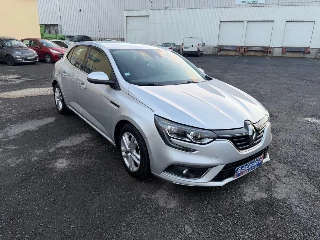 Renault Mégane gris alu vue 3/4 avant droit, avec phares LED et jantes alliage sur parking extérieur.