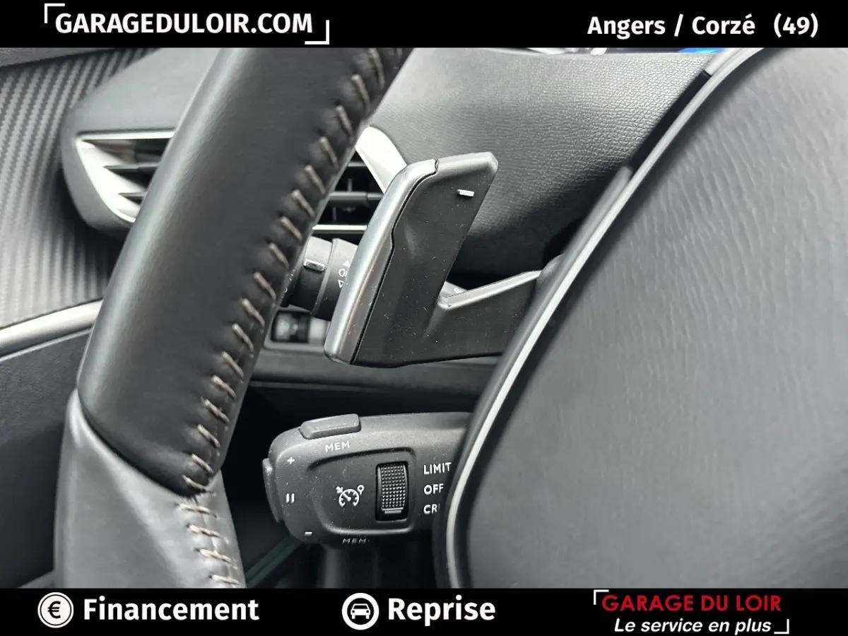 Gros plan sur le volant en cuir et les commandes de régulateur de vitesse du Peugeot 3008 blanc, intérieur côté conducteur.