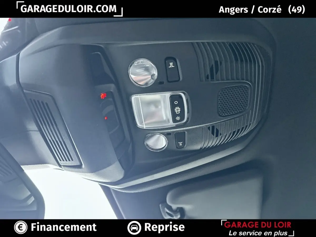 Vue rapprochée du plafonnier intérieur noir du Peugeot 3008 blanc 2024 avec commandes d’éclairage et haut-parleur intégré.