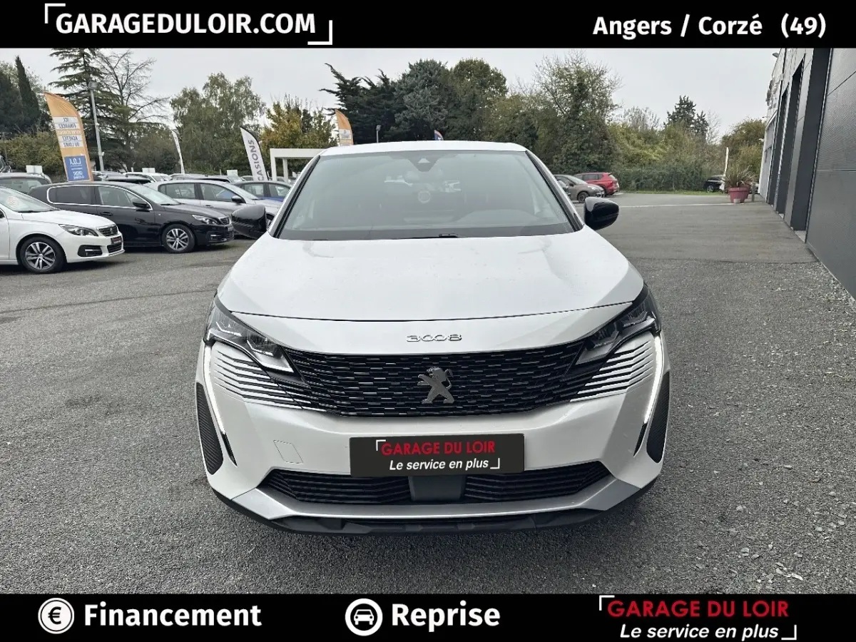 Vue avant d'un Peugeot 3008 blanc 2024 avec calandre noire et feux LED allumés sur un parking extérieur.