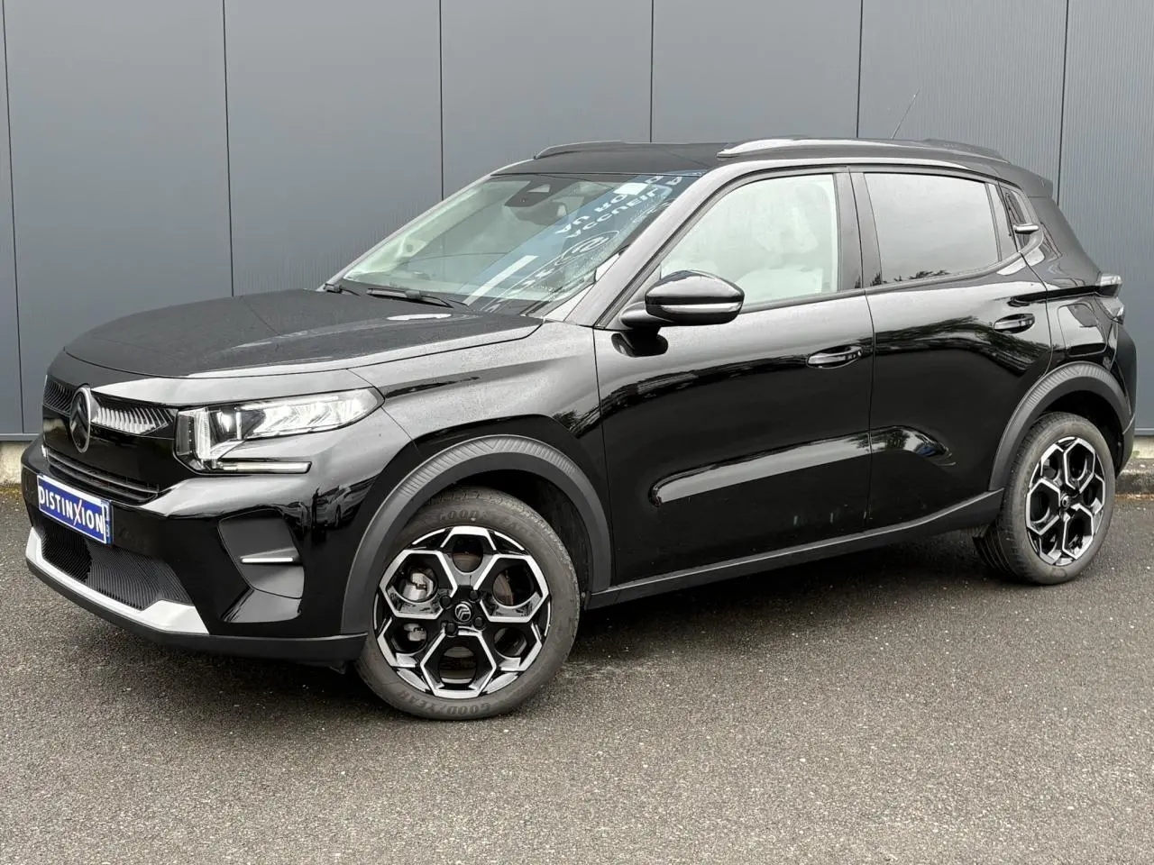 Vue 3/4 avant droite d'une Citroën C3 Turbo 100 Max noire Perla avec jantes alliage et barres de toit noires.